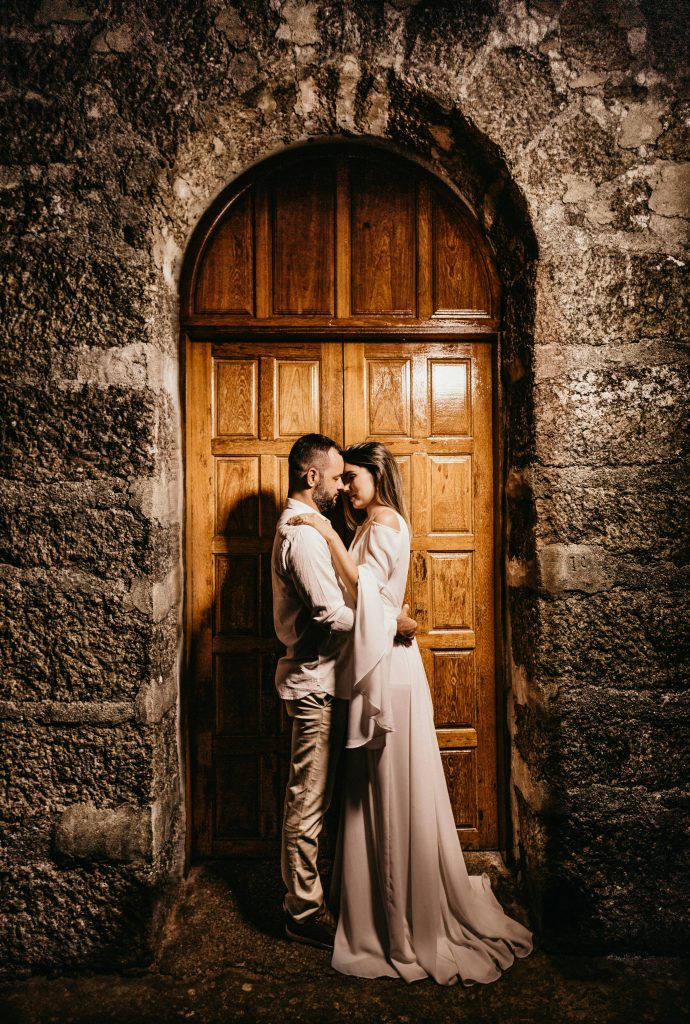 An intimate moment between a bride and groom embracing in front of a rustic wooden door.