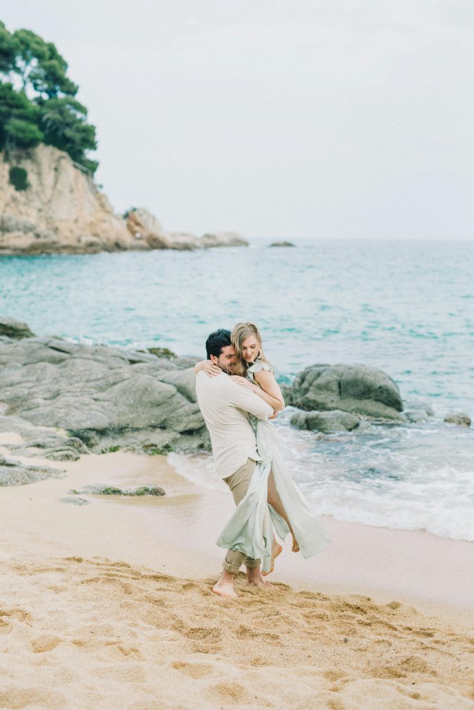 A loving couple shares an intimate moment on a sandy beach by the ocean.